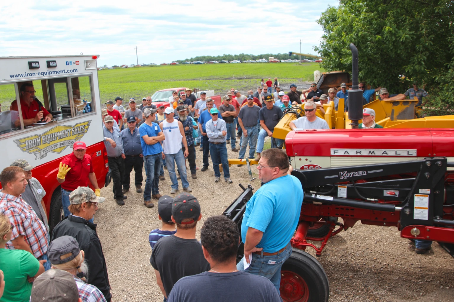 Auctioneer and visitors beside farm equipment
